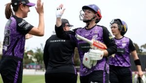 Hobart Hurricanes women players celebrating in purple WBBL kit
